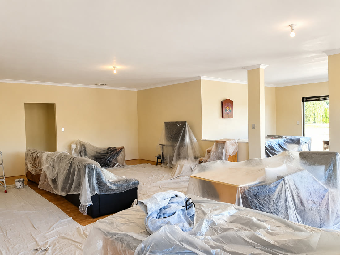 A living room carefully covered with drop sheets, prepped for painting